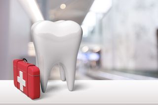 Large model of a tooth beside a red first-aid kit