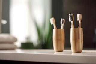 Four bamboo toothbrushes in cups on a bathroom counter